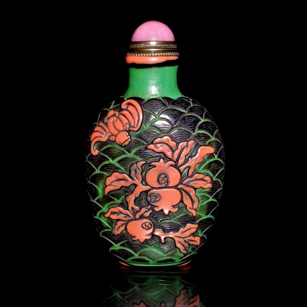 SUPERB SIGNED PEKING GLASS CARVED SNUFF BOTTLE: THE FINE BOTTLE IS SIGNED BY THE ARTIST. IT IS CARVED IN THREE LAYERS OF COLOR. IT FEATURES A BAT AND POMEGRANATES ON ONE SIDE AND AN ARCHAISTIC DRAGON AND PHOENIX. THE BACKGROUND IS CARVED WITH A WAV