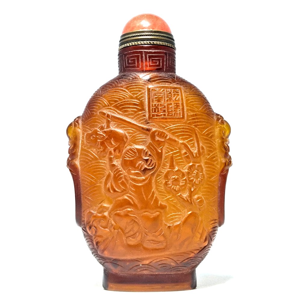 CARVED PEKING GLASS SNUFF BOTTLE AMBER COLOR SIGNED BOYS AT PLAY QIANLONG: THE BEAUTIFULLY CARVED SNUFF FEATURES BOYS AT PLAY ON BOTH SIDES WITH A WAVE PATTERN IN THE BACKGOUND. THE BOTTLE BEARS A QIANLONG .