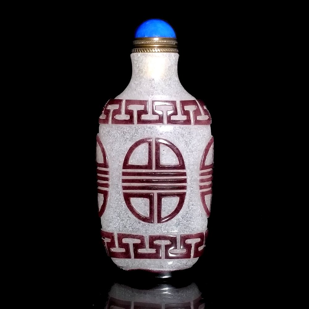 CHINESE SNOWFLECK PEKING GLASS SNUFF BOTTLE SHOU SYMBOL: THE EXCELLENT SNUFF BOTTLE IS FINELY CARVED IN BROWN OVER BUBBLE INFUSED SNOWFLECK GLASS. THE BOTTLE IS 3.2 INCHES TALL. STANDS ARE FOR DISPLAY ONLY, NOT INCLUDED UNLESS OTHERWISE STATED. PROPERTY OF
