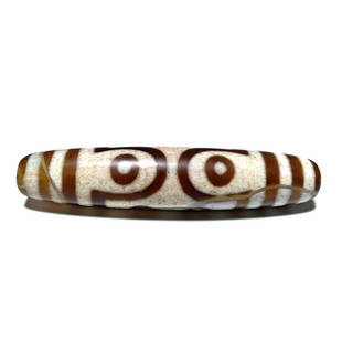 FANTASTIC MASTER DZI BEAD WHITE GROUND 67MM 7 EYES: THIS IS A FANTASTIC AND RARE MASTER DZI BEAD. IT FEATURES 7 EYES AND IT IS 67MM LONG. THE BEAD FEATURES EXCELLENT PATINA.