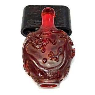 A FINELY CARVED CHERRY AMBER RESIN SNUFF BOTTLE DRAGON: THE BEAUTIFULLY CARVED BOTTLE DEPICTS A DRAGON AND A PHOENIX. IT IS 2.75 INCHES TALL. PROVENANCE: FLORIDA PRIVATE COLLECTOR.WE PROVIDE IN-HOUSE SHIPPING FOR YOUR CONVENIENCE. STANDS ARE FOR DISPLAY ON