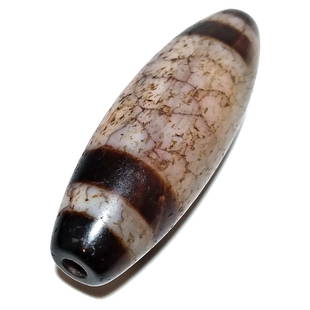 A RARE AND FABULOUS MASSIVE SINO TIBETAN AGATE DZI BEAD: THE FABULOUS MASTER BEAD IS 60MM LONG AND BARREL SHAPED. IT FEATURES 4 BROWN STRIPES AND A LOT OF BEAUTIFUL VEINS IN THE AGATE. PATINA AND WEAR FROM AGE. THIS IS A GREAT BEAD. PROVENANCE: PRIVATE COLL