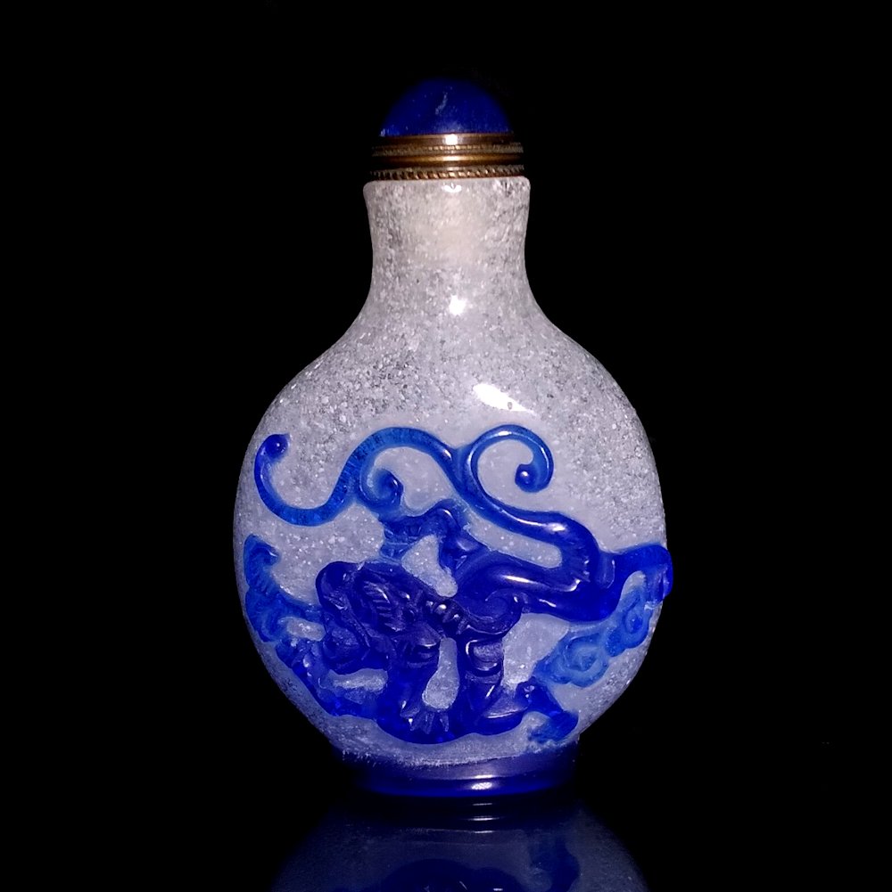 AN EXCELLENT CHINESE PEKING GLASS SNUFF BOTTLE KYLIN DRAGON: THE EXCELLENT BOTTLE IS CARVED IN 3 COLORS WITH FINE DETAIL FEATURING A KYLIN AND A DRAGON ON BUBBLE INFUSED GLASS. THE BOTTLE HAS A WELL DEFINED FOOT. IT IS 2.8 INCHES TALL. PROVENANCE: MAJOR PRIVATE