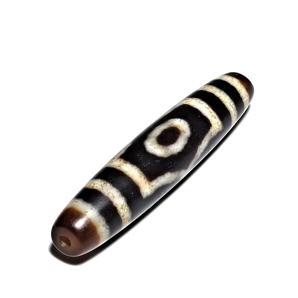FINE SINO TIBETAN AGATE DZI BEAD 3 EYES 52MM: THE FINE BID FEATURING 3 EYES WITHIN A STRIKING GEOMETRIC PATTERN. BEARING SATIN-LIKE PATINA. THE BEAD IS 52 MM LONG AND THE ENDS ARE A LIGHTER BROWN COLOR WHICH CREATES A GOOD CONTRAST. PROPERTY OF A