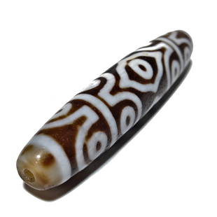 SUPERB VERY LARGE OLD AGATE DZI BEAD 15 EYE 77MM LONG: THE OUTSTANDING SINO- TIBETAN AGATE DZI BEAD WITH GREAT CLEAR LINES, 15 EYES AND 77 MM LONG, FEATURING A BAND OF EYE WITHIN EYE IN AN EXQUISITE PATTERN. IT BEARS WEAR AND PATINA FROM AGE.