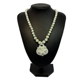 A VERY FINE CARVED CHINESE JADEITE NCEKLACE 21": THE EXQUISITE JADEITE NECKLACE HAS BEADS THAT GRADUATE FROM 8-10 MM.THE PENDANT IS CARVED ALL FROM ONE PIECE OF JADEITE. IT FEATURES A LOTUS AND A LOCK SHAPE. THE NECKLACE IS 21" LONG WITH A GILT