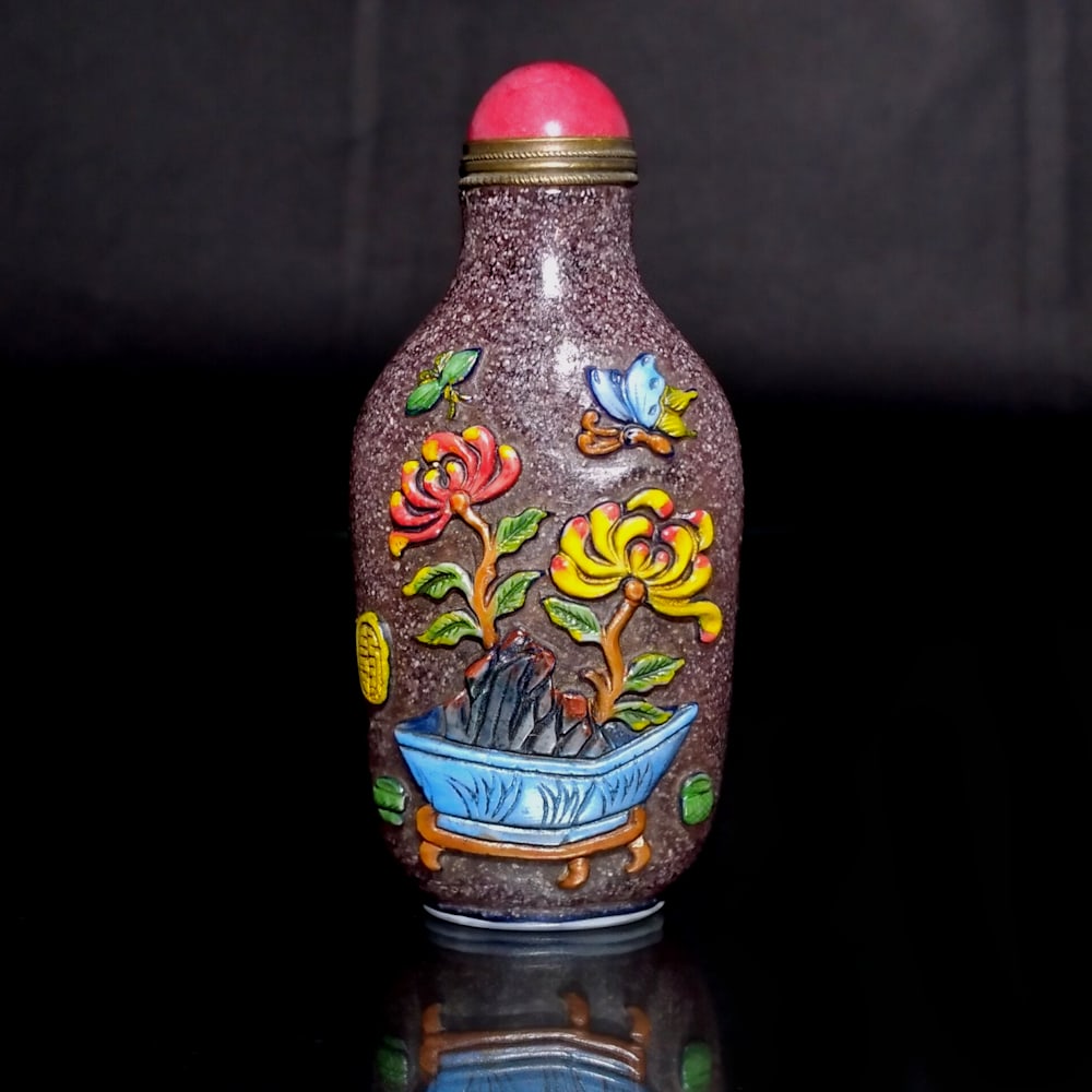 FINE CHINESE ENAMEL SNUFF BOTTLE INFUSED PURPLE GLASS BIRDS BUTTERFLIES: THE FINE CHINESE CARVED AND ENAMELED SNUFF BOTTLE IS ALSO ARTIST SIGNED. IT FEATURES FLORAL SCENES WITH BIRDS AND BUTTERFLIES. THE BOTTLE IS 3.25 INCHES TALL. STANDS ARE FOR DISPLAY ONLY, NOT INCLUDED