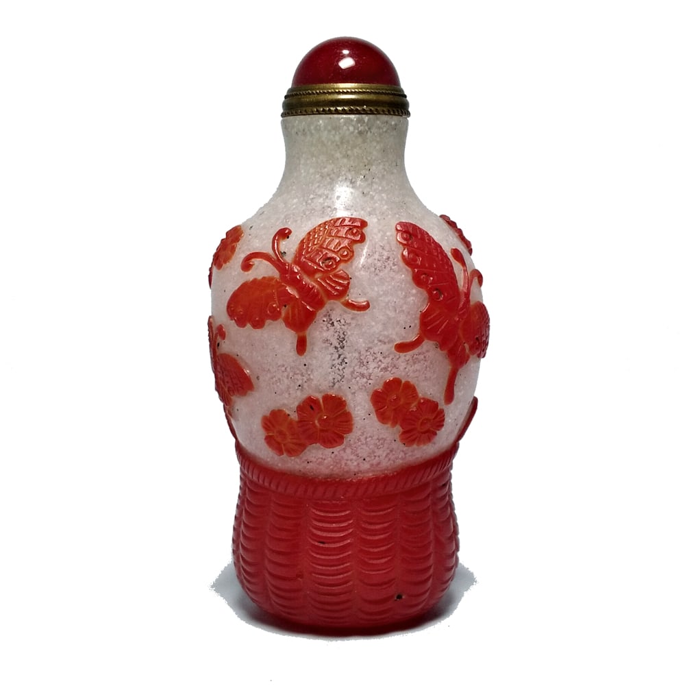 CHINESE PEKING GLASS SNUFF BOTTLE RED BASKETWEAVE: THE FINE CHINESE PEKING GLASS BOTTLE FEATURES A BASKETWEAVE AND BUTTERFLY PATTERN IN RED OVER SNOWSTORM GLASS BACKGROUND. THE BOTTLE FEATURES A WELL CARVED ROUND FOOT. IT IS 3.25 INCHES TALL. STANDS A