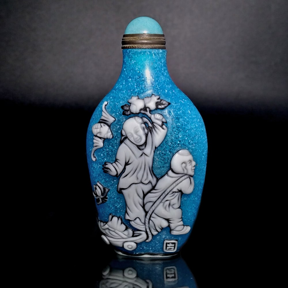 FINE CHINESE PEKING GLASS SNUFF BOTTLE CHILDREN AT PLAY: A FINE CHINESE SNUFF BOTTLE CARVED IN THREE LAYERS OF GLASS. THE BOTTLE FEATURES CHILDREN AT PLAY AND IT IS ARTIST SIGNED. IT IS 3.4 INCHES TALL. STANDS ARE FOR DISPLAY ONLY, NOT INCLUDED UNLESSOTHERW