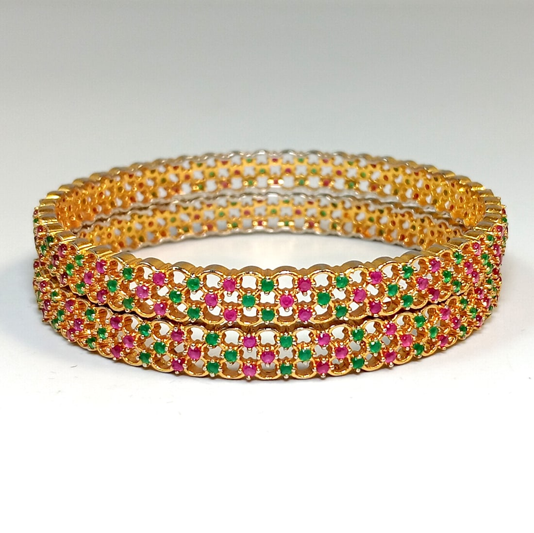 A PAIR OF BANGLES WITH GENUINE RUBIES AND EMERALDS: OFFERED HERE IS A PAIR OF VINTAGE BANGLES FROM INDIA. THEY ARE SO BEAUTIFULLY ADORNED WITH GENUINE RUBIES AND EMERALDS, ELECTRONICALLY TESTED WITH THE PRESIDIUM GEM TESTER. THEY ARE GOLD TONE. THE INN