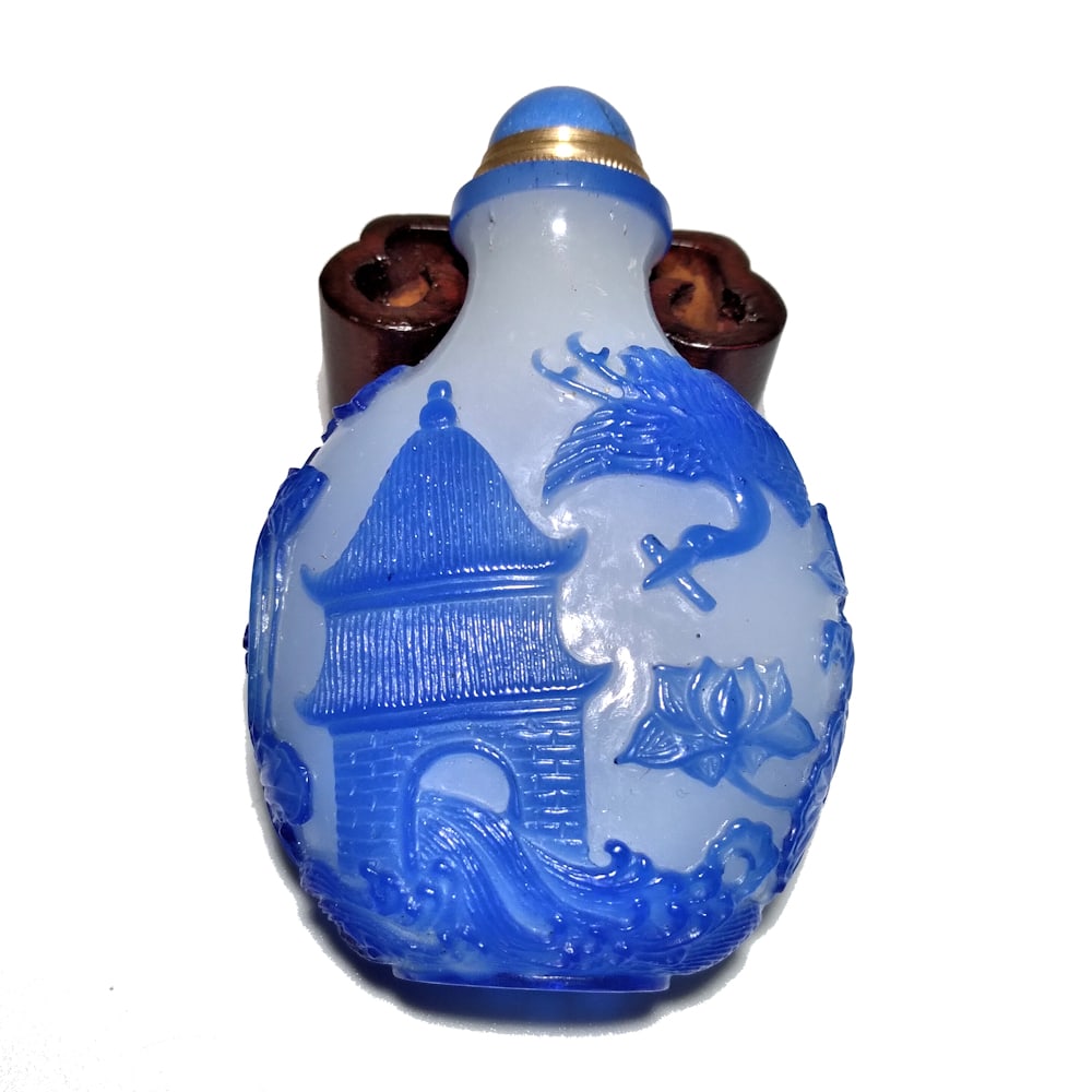 EXQUISITE CHINESE PEKING GLASS SNUFF BOTTLE STORK FISH LOTUS: THE EXQUISITE CHINESE CARVED SNUFF BOTTLE IS BLUE OVER BUBBLE INFUSED GLASS. THE BOTTLE IS CARVED ALL AROUND DEPICTING STORK, LOTUS, FISH. THE BOTTLE IS 2.9" TALL. STANDS ARE FOR DISPLAY ONLY, NOT INC