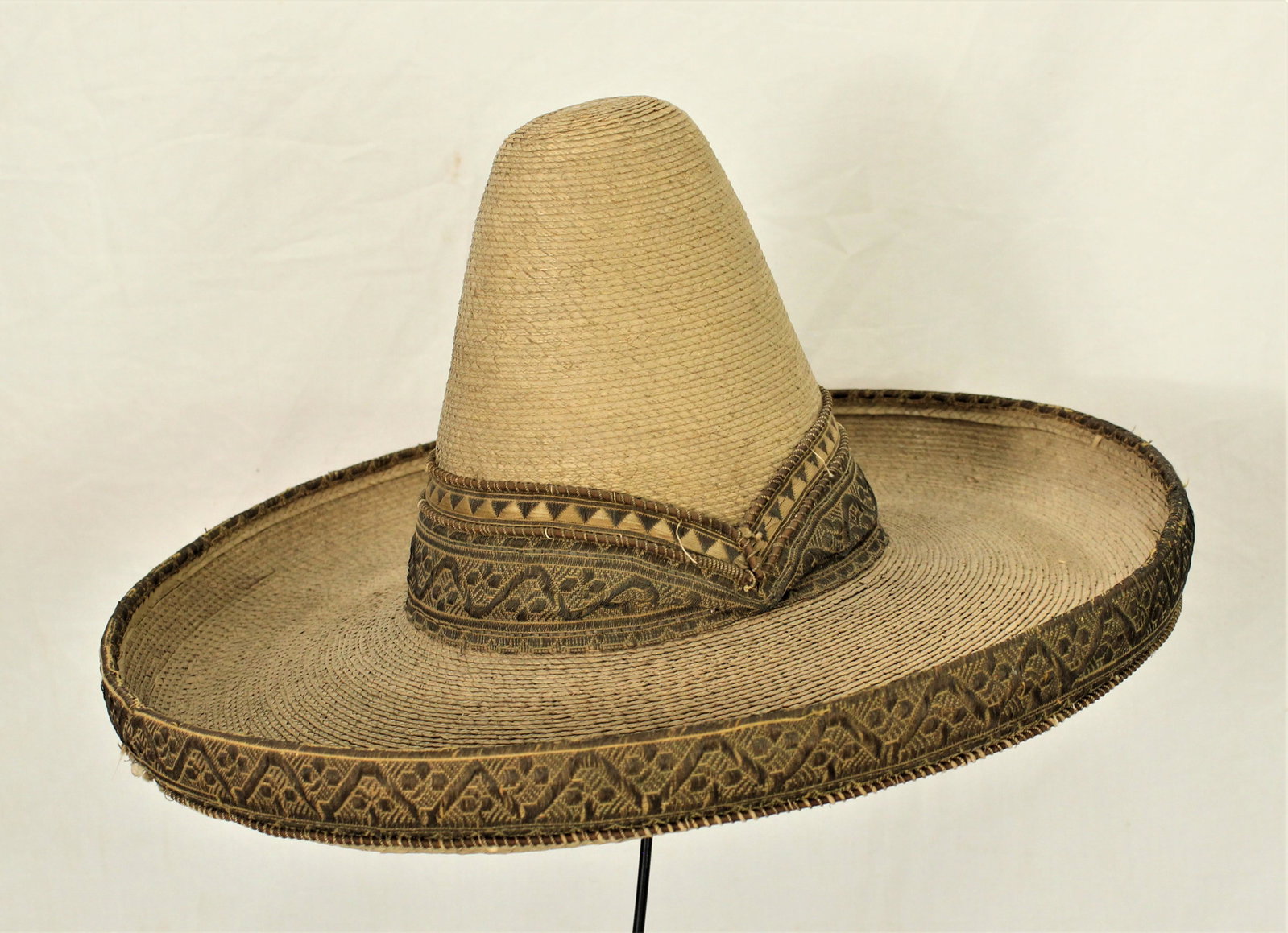 Mexican Sombrero: Wonderful large straw sombrero with tall peaked crown, 5" brim with tall decorative fabric bound elaborate rolled edge and hatband. Category: Hat