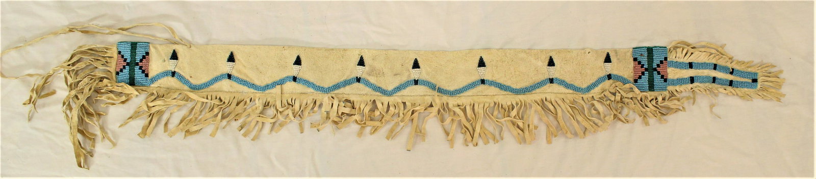Beaded Pipestem Bag: Out of the ordinary turn of the Century Plains Indian tanned hide pipe stem bag with attractive beadwork design and full perimeter fringe, measuring 3" x 36". Category: Native American