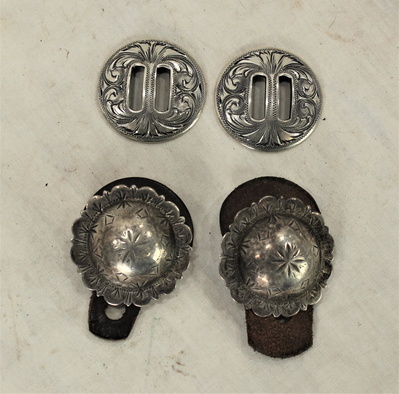 Two Pairs Silver Conchos: A lot of two pairs of outstanding conchos; 1) Clint Orms marked slotted 1 1/2" finely engraved silver conchos, 2) well marked Visalia engraved and scalloped edge loop back 1 3/4" conchos.