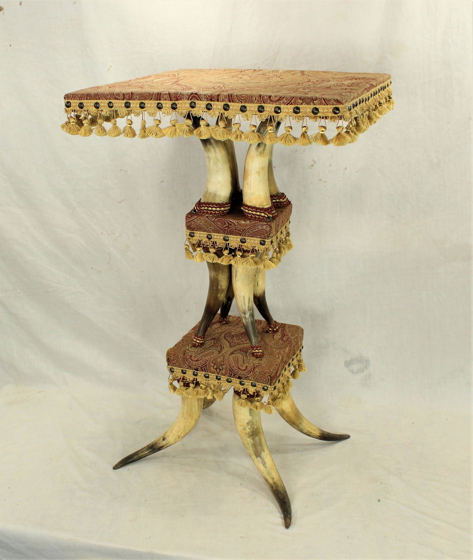 Longhorn Table: A beautiful decorative Victorian antique three tiered longhorn parlor table with paisley upholstery and fringe.