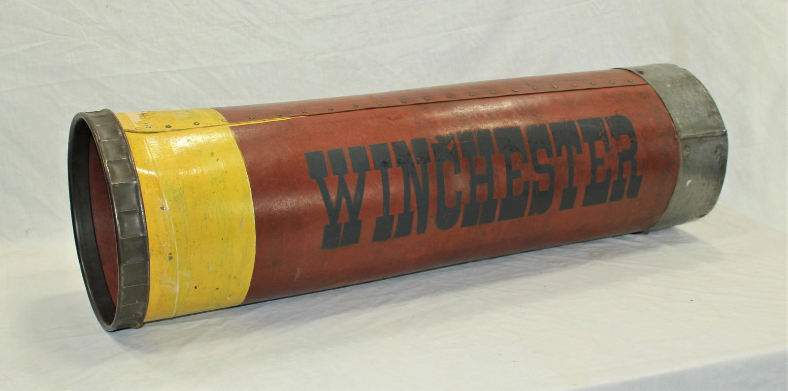 Antique Winchester Store Display: A super neat original large store display canister in the shape of a shotgun shell, with metal bound edges and the word "Winchester" stenciled the length of it. With great patinaed color. Dimensions 1