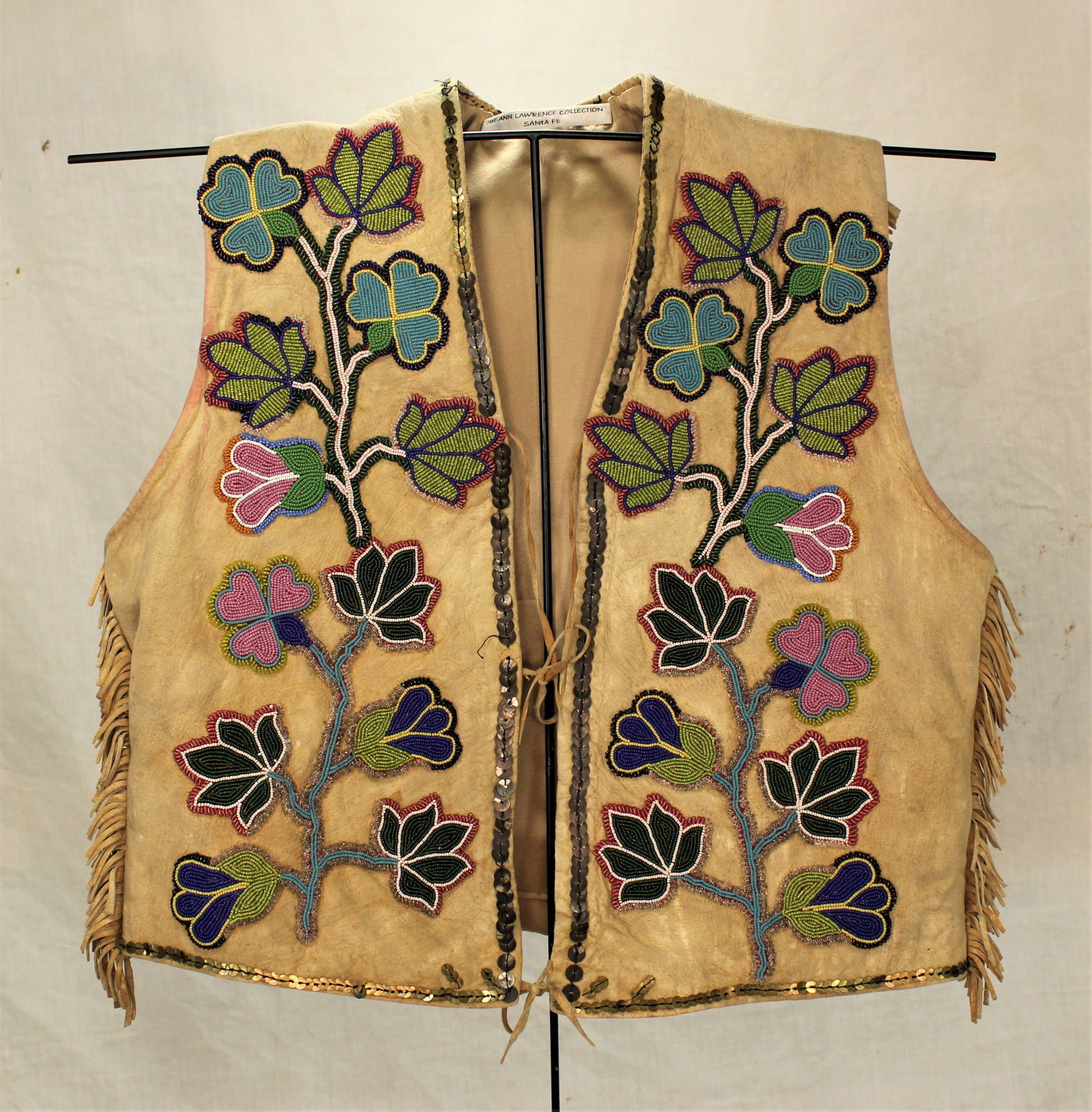 Striking Santee Sioux Vest: Wonderful turn of the Century vest with very uncommon style, with a flower beaded front and fringed and full coverage beaded geometric pattern back. Displaying great eye appeal.