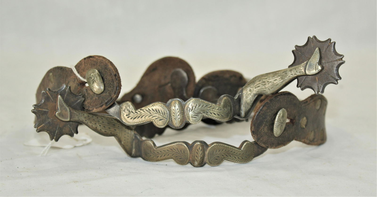 Uncommon McChesney Spurs: Extremely scarce #40 pattern spurs, single mounted with peanut buttons and web rowels, and original straps.