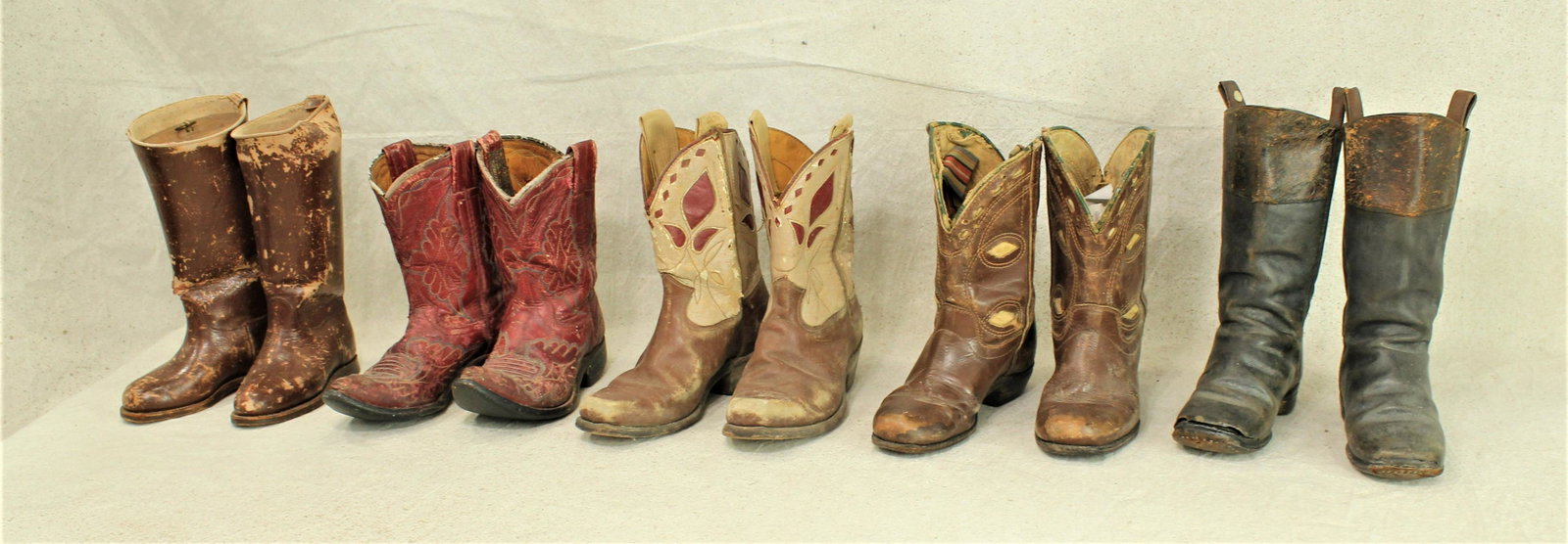 Grouping of Kids Boots: Five pairs of a variety of kids boots, with early 1870's stovepipe boots, 1920's riding boots, and three pair of decorative 1940's cowboy boots with cloth pulls.