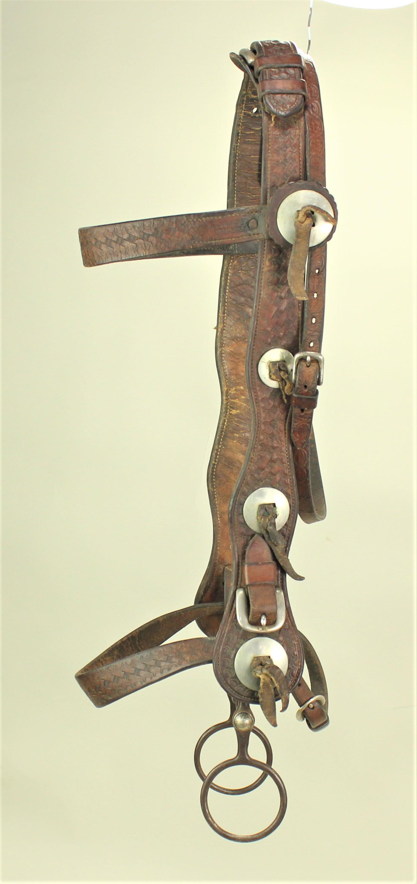 R.T. Frazier Headstall: Remarkable massive wide cheek bridle with full basket stamp tooling, maker's stamp, and adorned with nickel conchos. Showing near mint condition and accompanied by an iron globe bit.