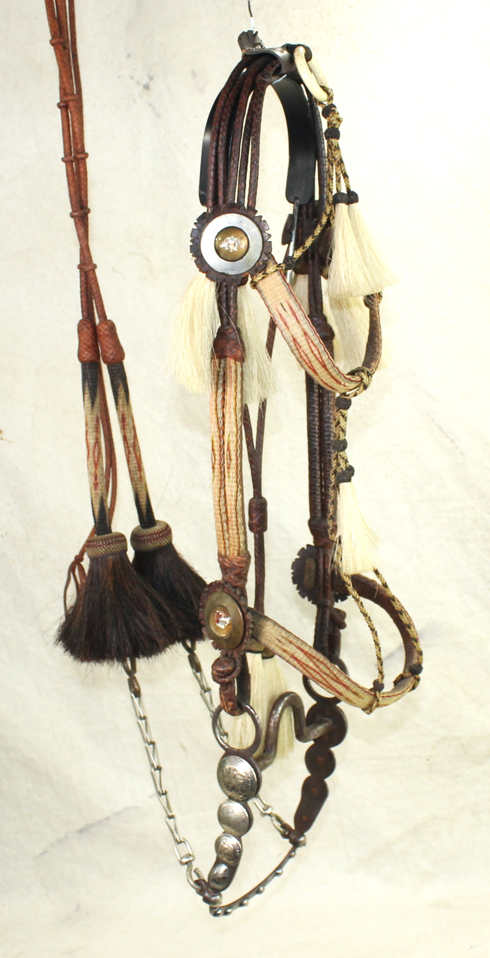 Rawlins Horsehair Bridle: With great Western flavor, this multi-colored hitched horsehair bridle is combined with finely braided leather, and decorated by glass rosettes and a very attractive bit with graduated domed coins.