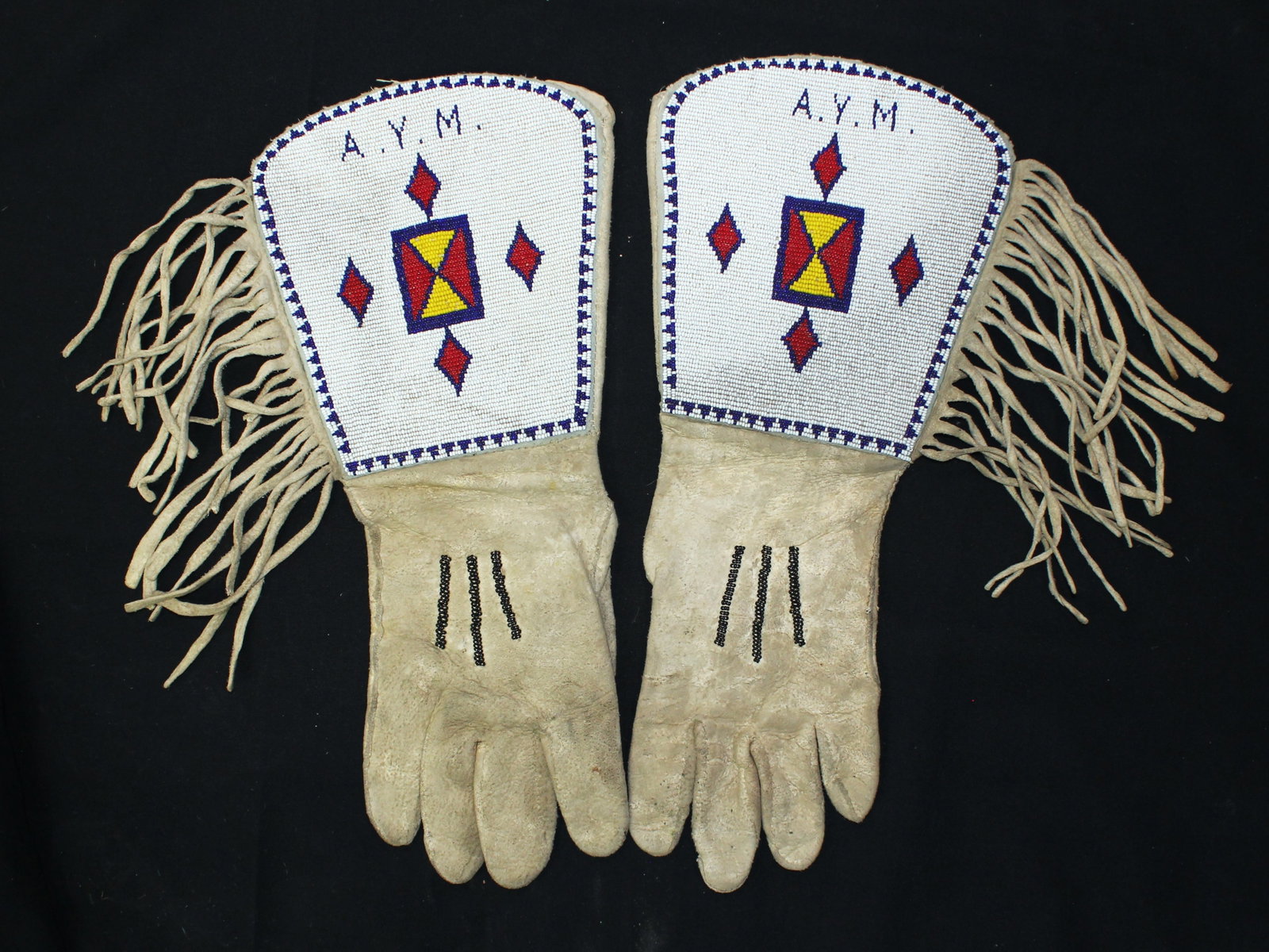 Blackfoot Beaded Gauntlets: A nearly unworn pair of Northern Plains Indian gauntlets with fully beaded cuffs, using cobalt blues and steelys, and fringed edge.