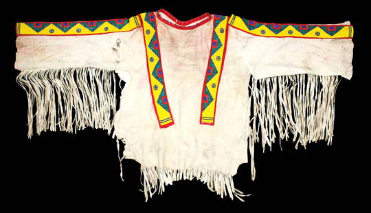 An eye catching vintage Northern Plains hide shirt with applied beaded strips and extensive long: An eye catching vintage Northern Plains hide shirt with applied beaded strips and extensive long fringe. A great display piece with eye appeal.