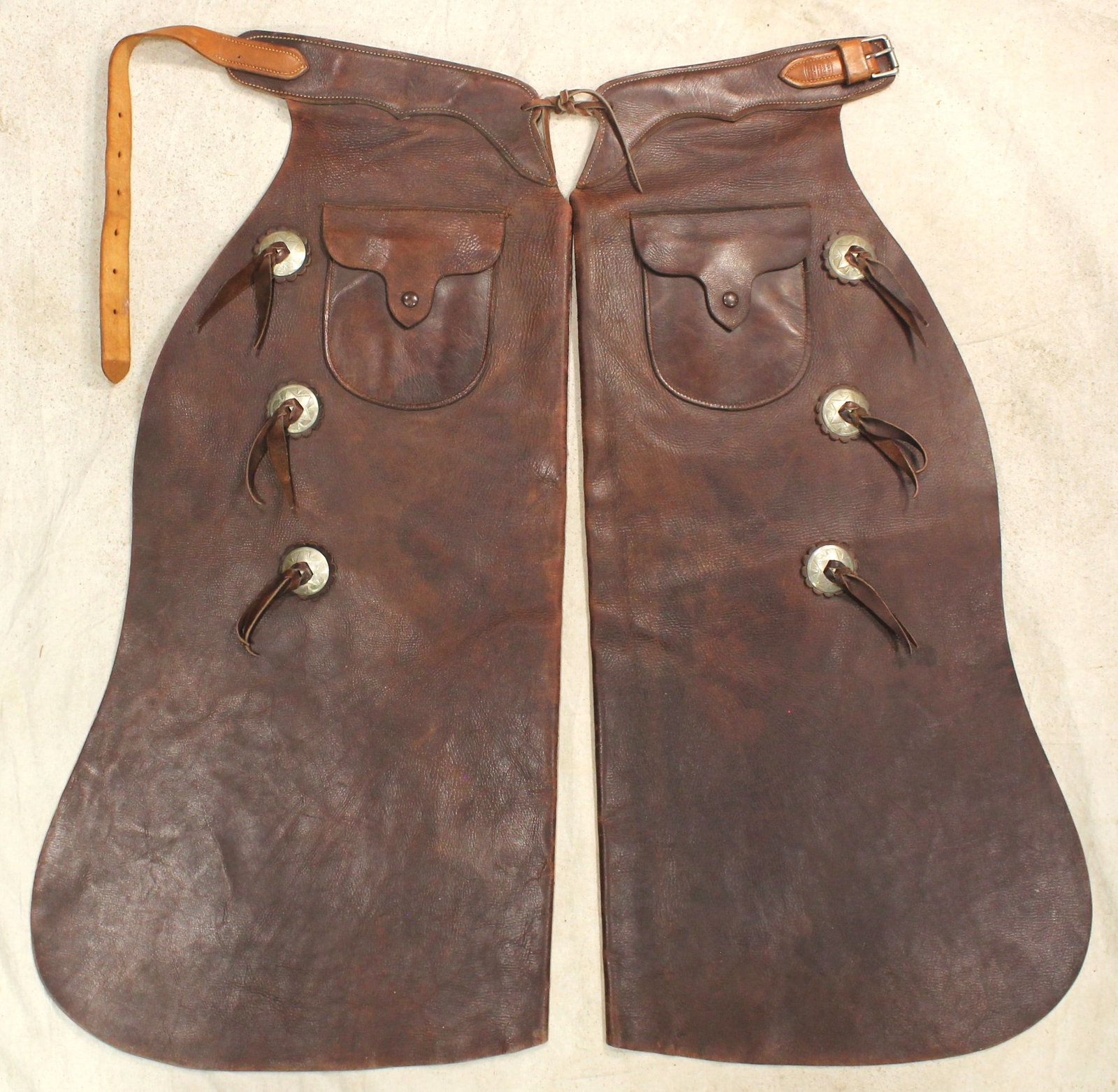 Powder River Batwing Chaps: A pair of nearly unused large Denver Dry Goods marked batwing chaps, adorned with saddle string conchos and exterior pockets. With terrific color and maker marked belt.