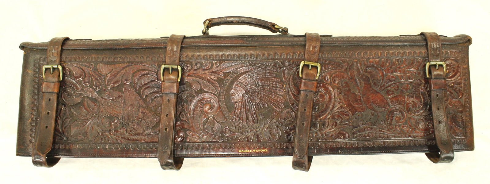 Outstanding Carved Leather Rifle Case: Exceptional hand-carved leather double rifle case, inscribed to Walter E. Wiltong, noted Colorado outdoorsman. Richly decorated with a central Plains Indian chief portrait surrounded by elaborate