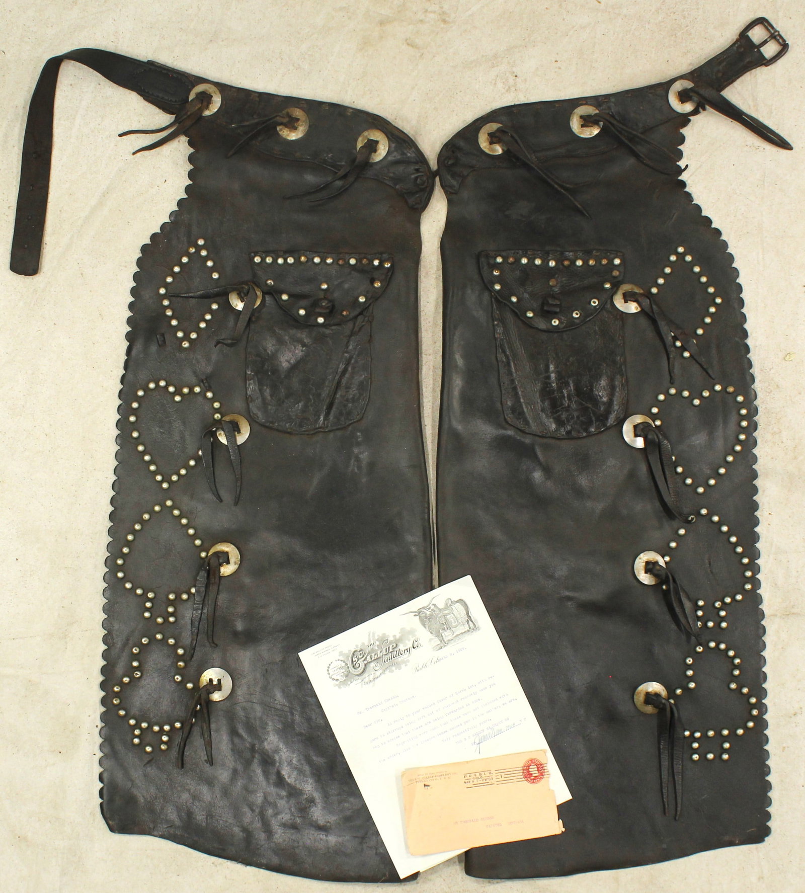 S.C. Gallup Studded Chaps: Niceley made batwing chaps from a scarce maker, featuring a decorative scalloped edge, studded card suit pattern, nickel conchos, and large pockets. Accompanied by the rare original purchase receipt a