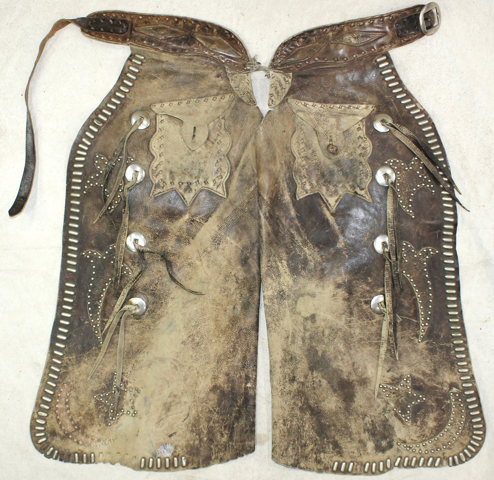 Studded Batwing Chaps: A showy pair of studded batwing chaps with great features of nickel conchos, two-tone applied leather figures, and uncommon decorative nickel studs.