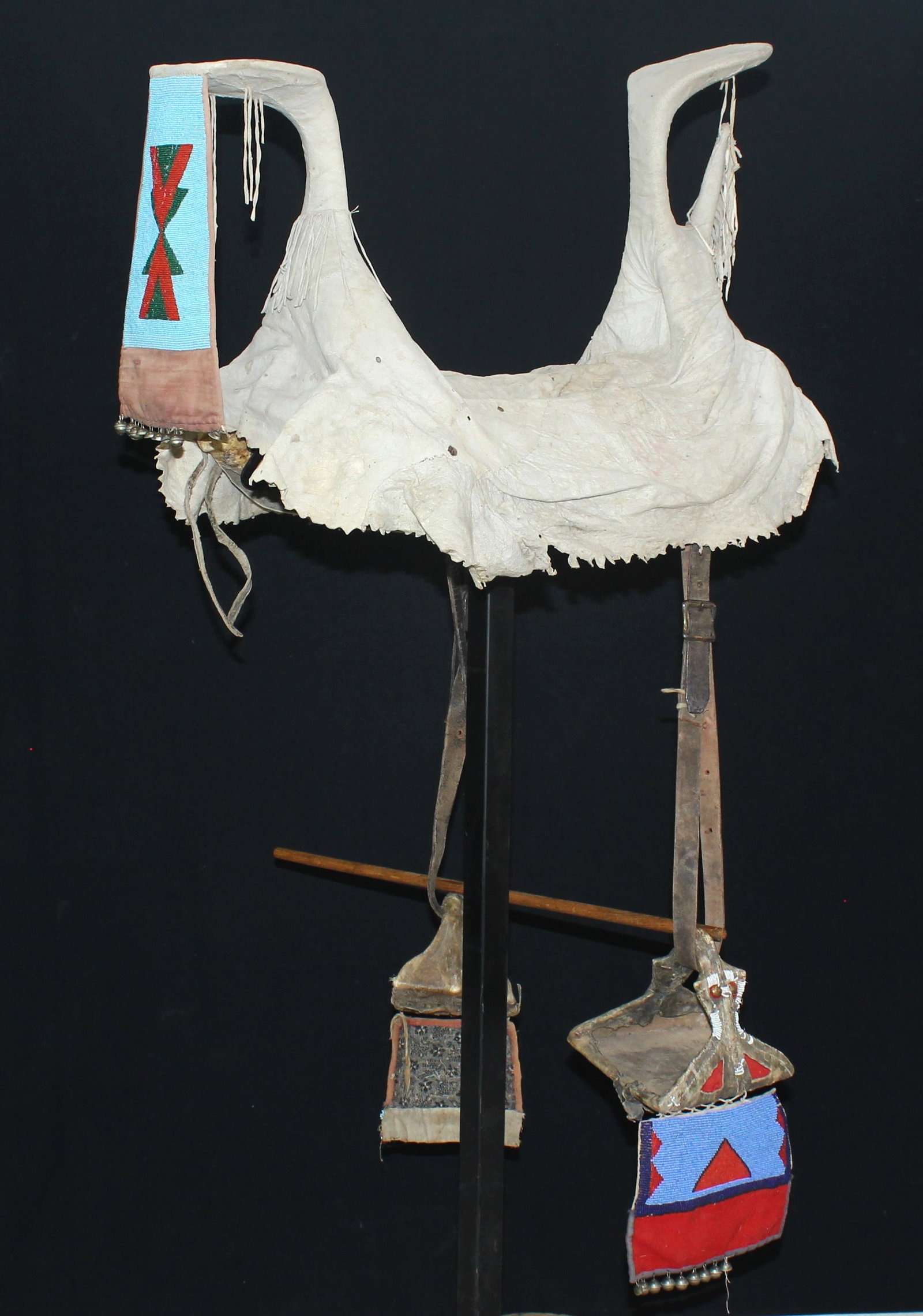Crow Indian Beaded Saddle: Large Crow saddle with soft tanned hide cover, with exaggerated large horns at each end, adorned with a terrific beaded drop, with original stirrup leathers and completed by attractively beaded mis-ma