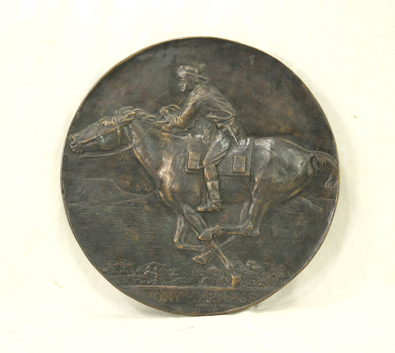 Proctor Pony Express Bronze: Circular bronze plaque depicting a mounted Pony Express rider at full gallop, signed “A. Phimister Proctor.” Measuring 16” in diameter. A desirable Western art casting.