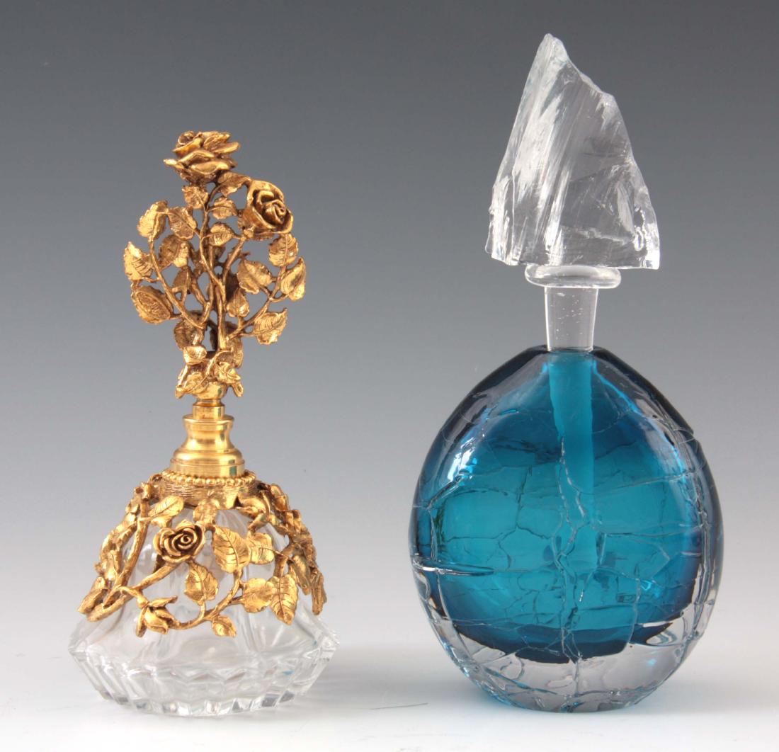 A LATE 20TH CENTURY BLUE ART GLASS SCENT BOTTLE BY: A LATE 20TH CENTURY BLUE ART GLASS SCENT BOTTLE BY BOB CROOKS with cracked ice stopper 18cm high x 9cm wide together with a gilt metal mounted cut glass scent bottle 15.5cm high, 7.5cm wide.