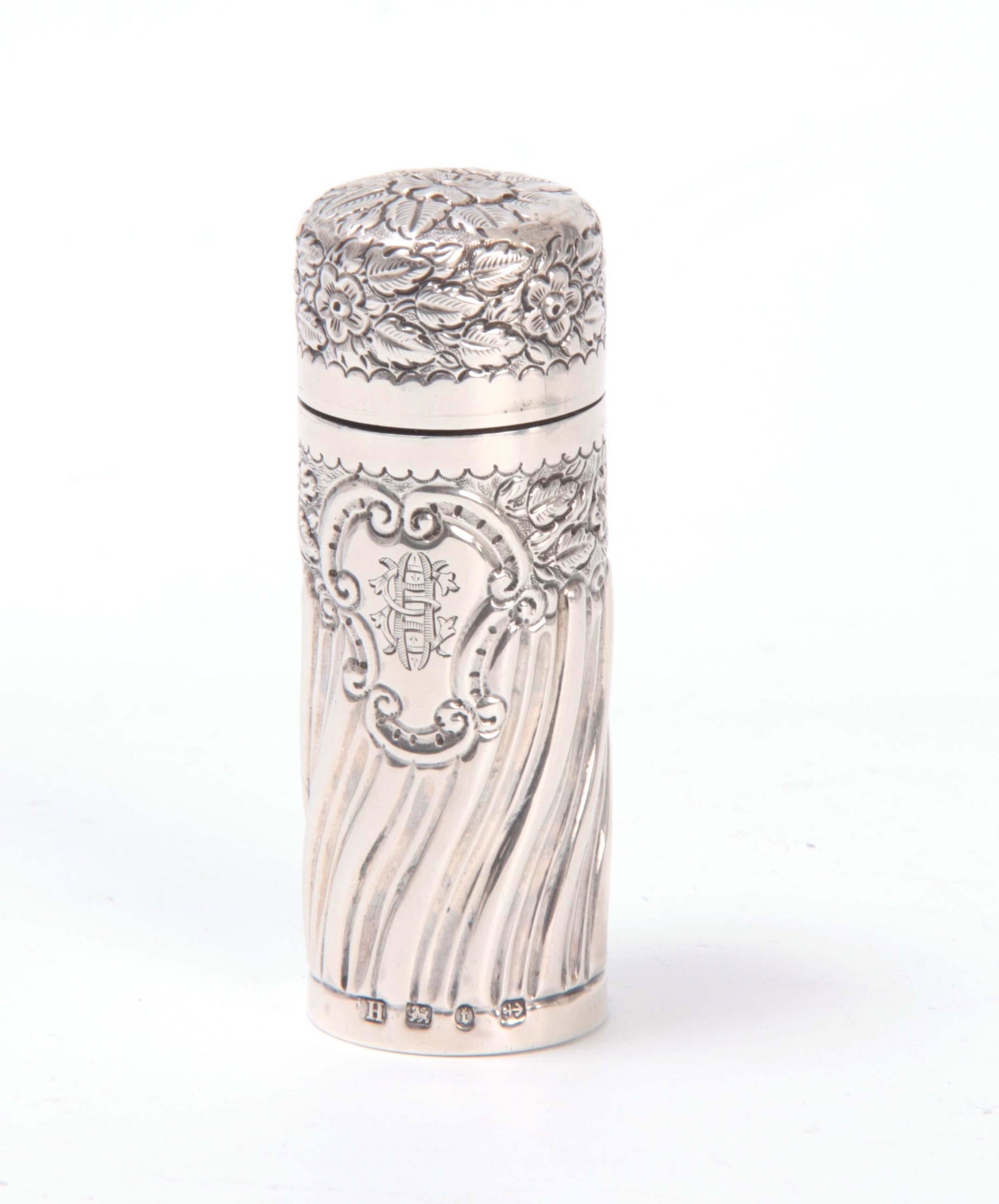 A VICTORIAN SILVER CASED CYLINDRICAL SMELLING SALT: A VICTORIAN SILVER CASED CYLINDRICAL SMELLING SALTS BOTTLE with swirl fluted lower body and monogrammed cartouch beneath bands of flowering leaf work 8cms high Birmingham 1893