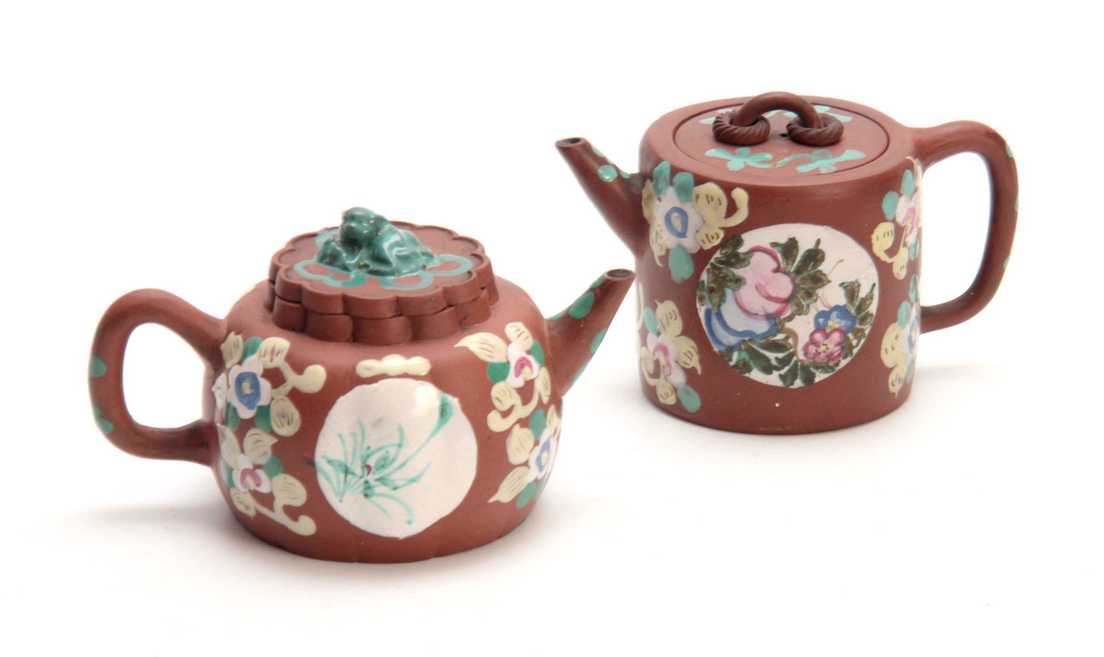 TWO CHINESE REPUBLIC PERIOD REDWARE TEAPOTS the squat: TWO CHINESE REPUBLIC PERIOD REDWARE TEAPOTS the squat rounded example enamelled with floral and medallion sprays beneath a monkey finial to the lid; the other cylindrical example with similar decorati