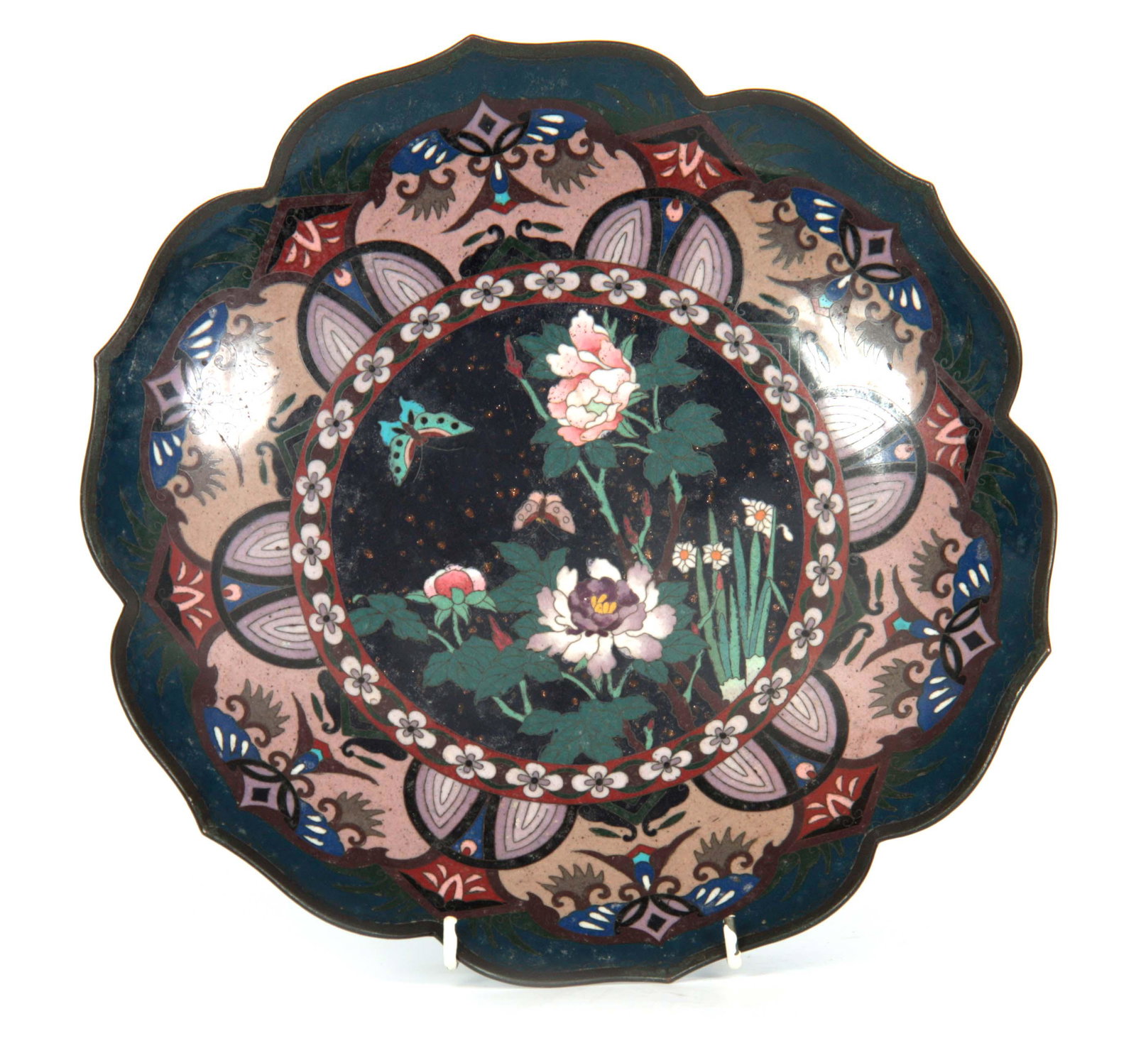 A JAPANESE MEIJI PERIOD CLOISONNE ENAMEL CHARGER w: A JAPANESE MEIJI PERIOD CLOISONNE ENAMEL CHARGER with a shaped scalloped edge, having blue and purple ground panels decorated with flowering tree blossom and butterflies 30cm diameter.