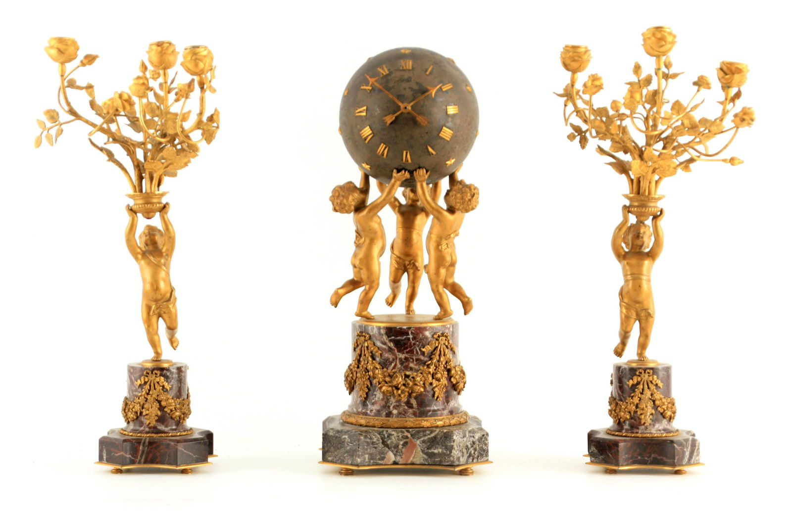A LATE 19TH CENTURY ORMOLU AND MARBLE FIGURAL CLOCK: A LATE 19TH CENTURY ORMOLU AND MARBLE FIGURAL CLOCK GARNITURE modelled as three cherubs raised on an ormolu-mounted veined marble base supporting a patinated globular clock with applied gilt stars and