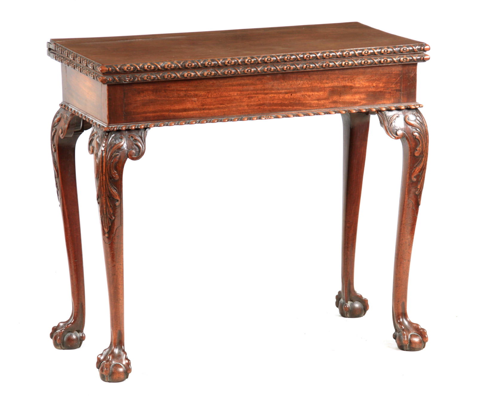 A MID 18TH CENTURY MAHOGANY CARD TABLE IN THE MANNER OF: A MID 18TH CENTURY MAHOGANY CARD TABLE IN THE MANNER OF THOMAS CHIPPENDALE the figured top having flower head carved moulded edge revealing a dark blue baize interior; standing on finely carved leaf m