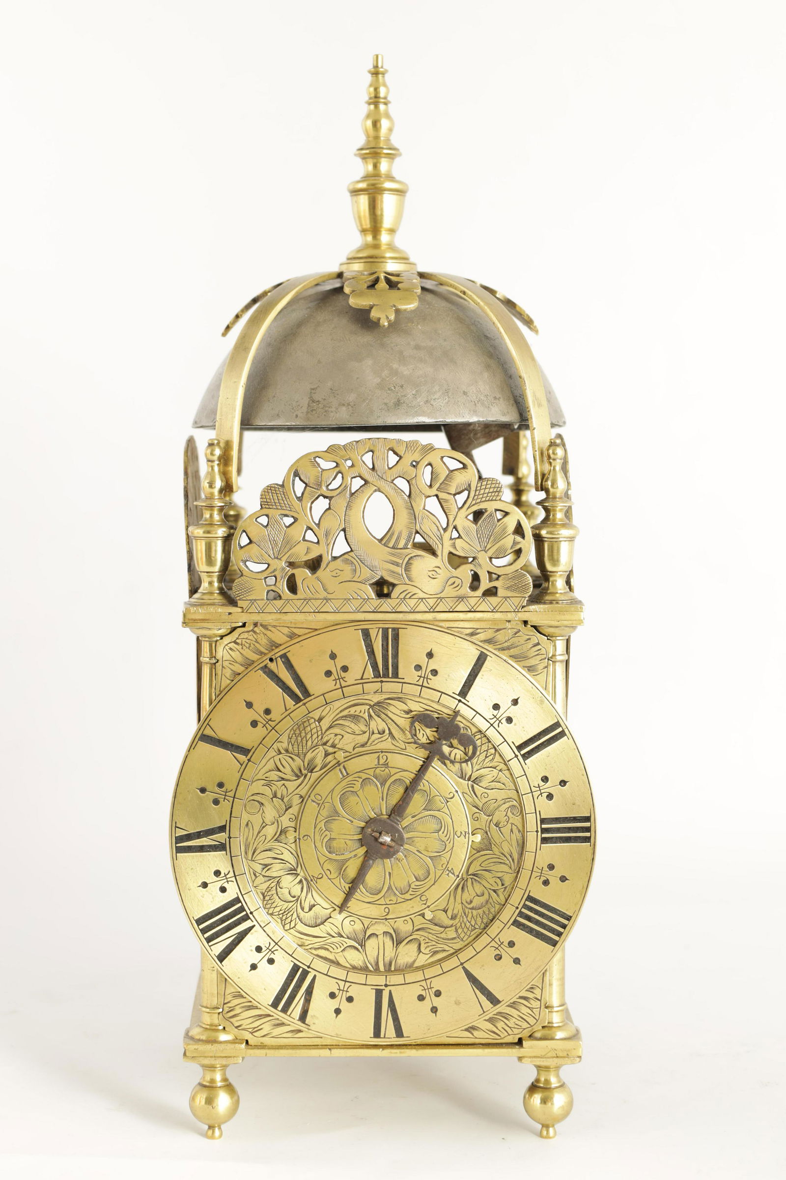 A FINE CHARLES II BRASS LANTERN CLOCKÊthe posted f: A FINE CHARLES II BRASS LANTERN CLOCKÊthe posted frame with side doors, engraved fretwork crestings and strapped bell surmounted by a large final above a Roman chapter ring with quarter hours marking