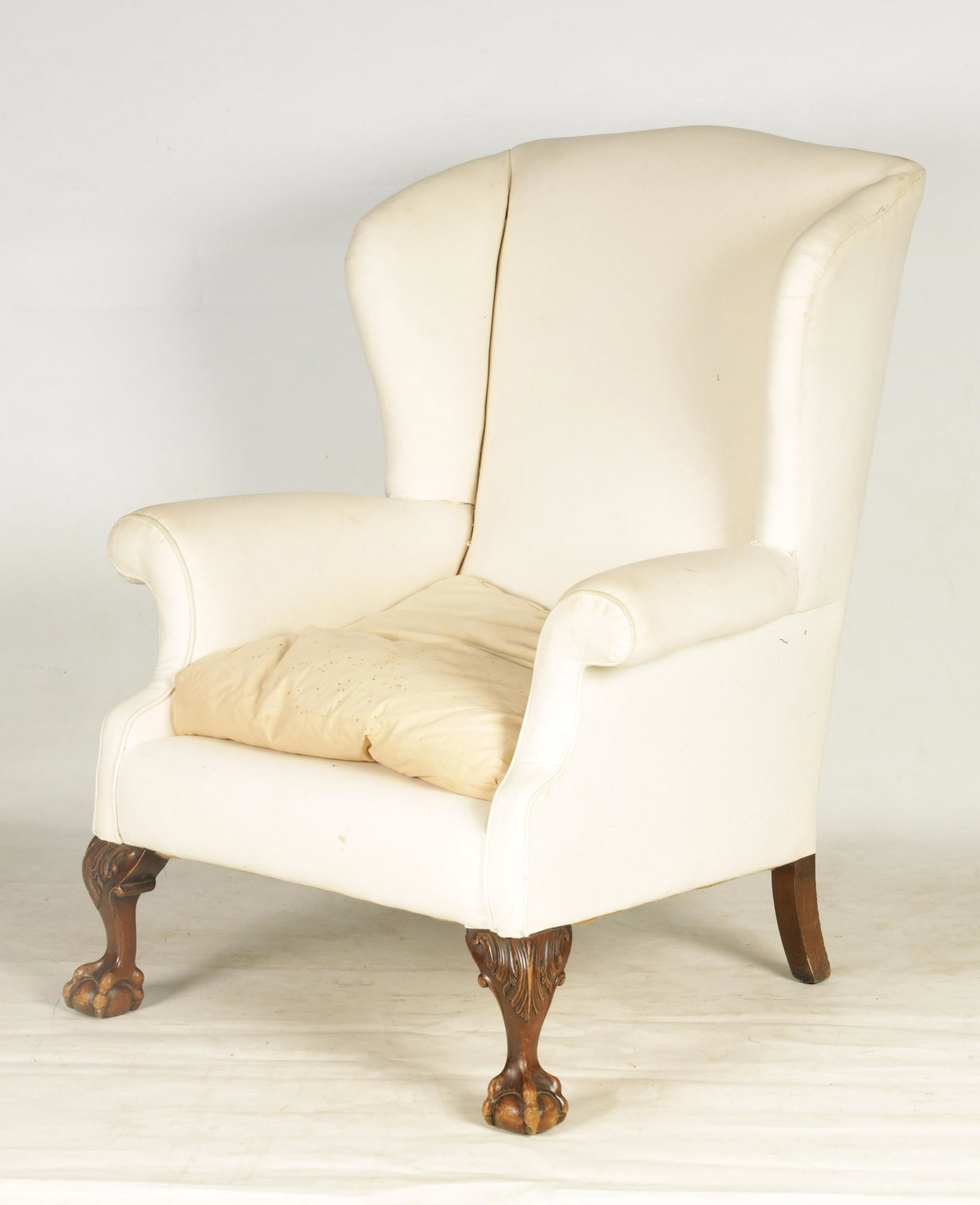 A LATE 19TH CENTURY GEORGE I STYLE WINGBACK UPHOLS: A LATE 19TH CENTURY GEORGE I STYLE WINGBACK UPHOLSTERED ARMCHAIR with mahogany leaf carved cabriole legs raised on ball and claw feet; with loose cushion 100cm high 81cm across