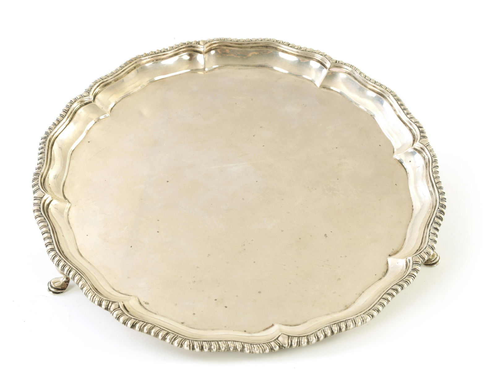 A LATE VICTORIAN SILVER SALVER: A LATE VICTORIAN SILVER SALVER with raised gadrooned edge standing on three hoof feet app. weight 560g - Charles Stuart Harris. London 1896(25.5cm diameter)