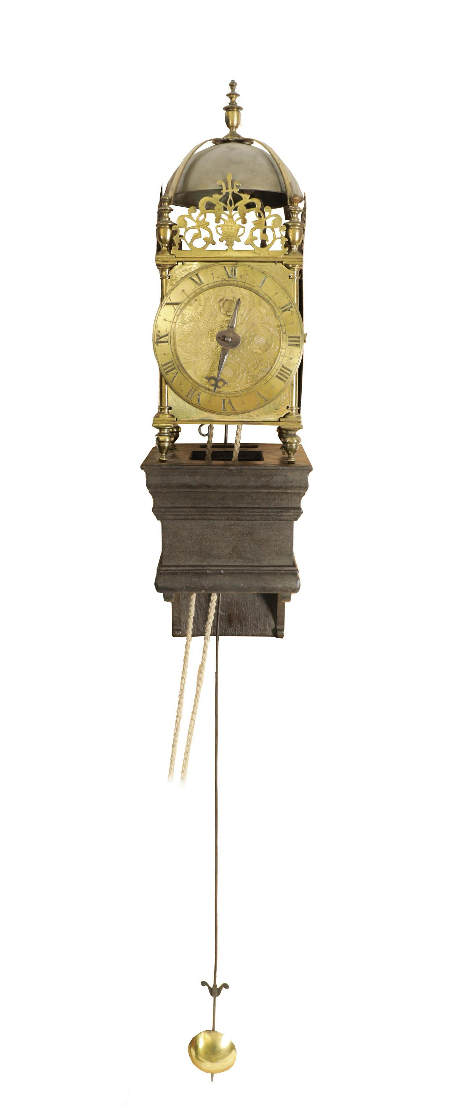 A FIRST PERIOD ENGLISH BRASS LANTERN CLOCK: A FIRST PERIOD ENGLISH BRASS LANTERN CLOCK the posted frame with side doors, engraved masked fretwork crestings and strapped bell surmounted by a large final above a narrow Roman chapter ring with qua