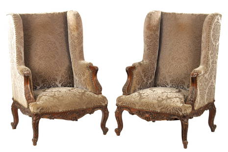 A PAIR OF 18TH CENTURY FRENCH OVERSIZED CARVED WALNUT UPHOLSTERED WINGBACK ARMCHAIRS: A PAIR OF 18TH CENTURY FRENCH OVERSIZED CARVED WALNUT UPHOLSTERED WINGBACK ARMCHAIRSS with leaf-carved rococo style frames, shaped backs and side arms; standing on slender cabriole legs. (77cm wide 11