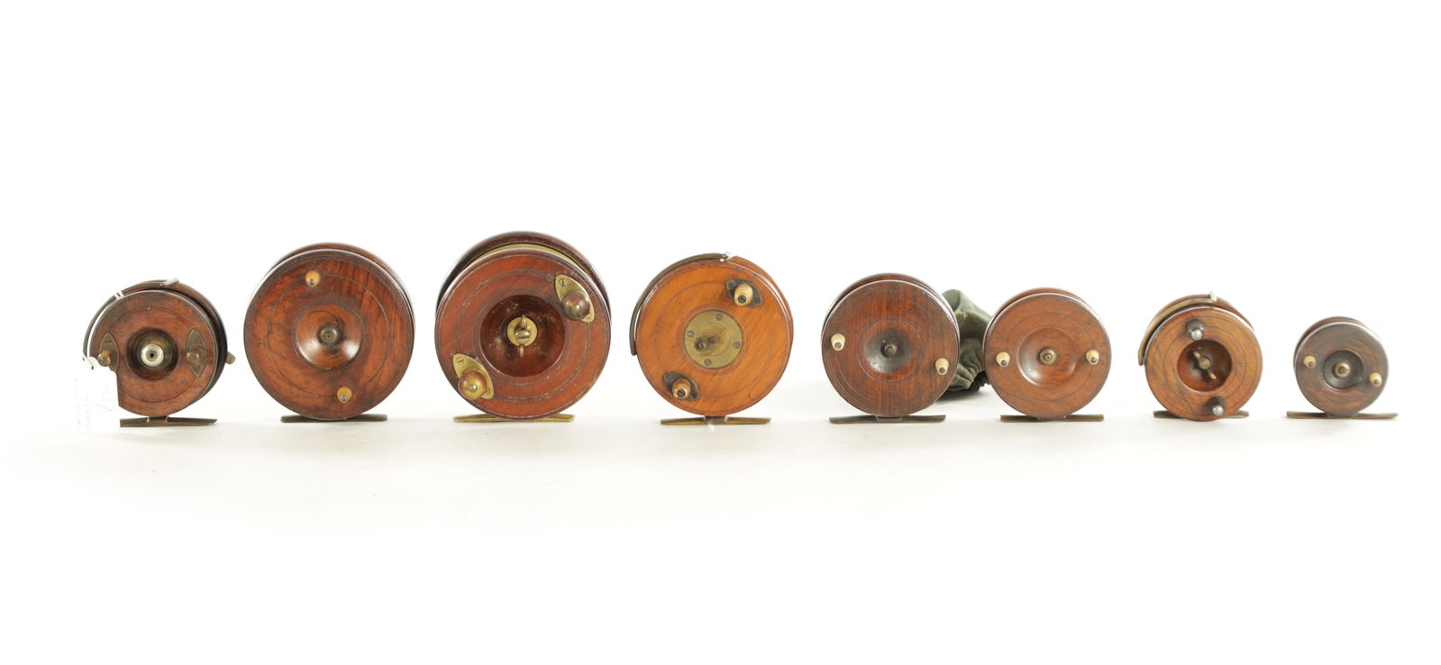 A COLLECTION OF EIGHT VINTAGE WOOD AND BRASS FLY FISHING REELS: A COLLECTION OF EIGHT VINTAGE WOOD AND BRASS FLY FISHING REELS, including a 3 1/4" Hardy and a 4" Heatons. (8)
