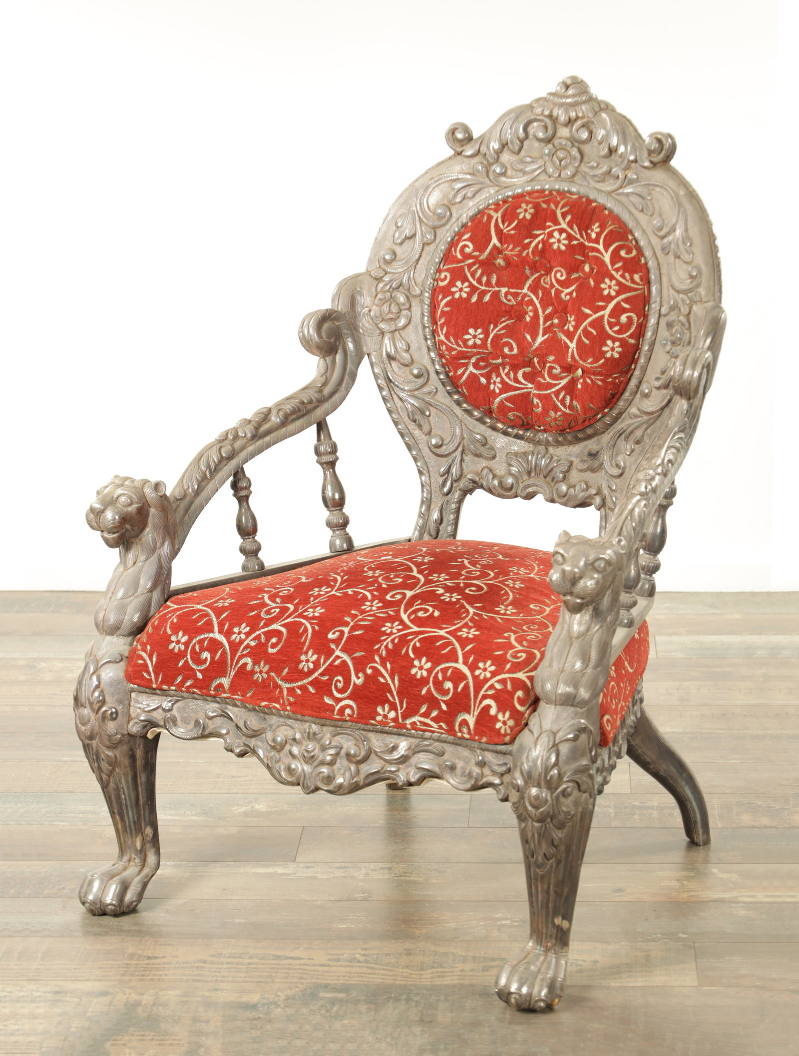 A 19TH CENTURY INDIAN CARVED HARDWOOD PEWTER COVERED UPHOLSTERED ARMCHAIR: A 19TH CENTURY INDIAN CARVED HARDWOOD PEWTER COVERED UPHOLSTERED ARMCHAIR of orange design with lion mask head arms and front legs; button upholstered back and seat (72cm wide 99cm high )