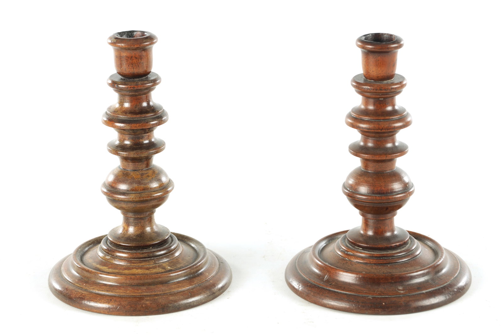 A PAIR OF 19TH CENTURY TURNED WALNUT TREENWARE CANDLESTICKS: A PAIR OF 19TH CENTURY TURNED WALNUT TREENWARE CANDLESTICKS having knopped turned stems and dished bases (19cm high)