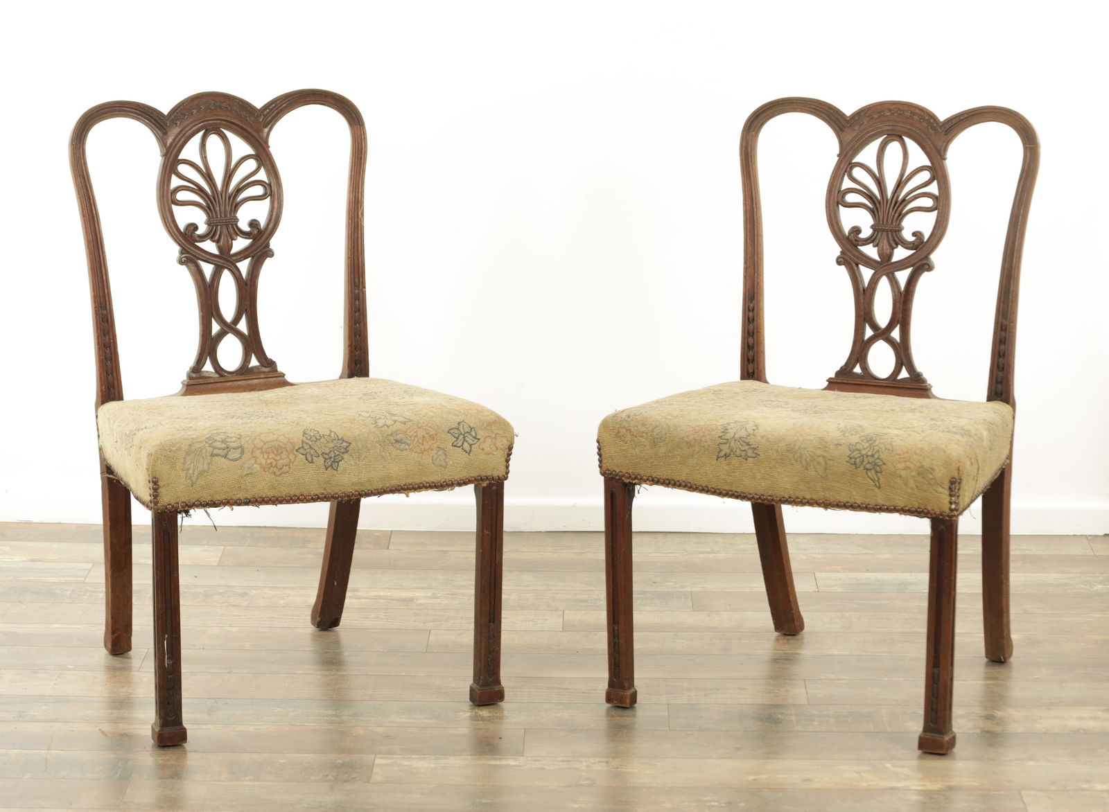 AN UNUSUAL PAIR OF GEORGE III MAHOGANY SIDE CHAIRS IN THE MANNER OF THOMAS CHIPPENDALE: AN UNUSUAL PAIR OF GEORGE III MAHOGANY SIDE CHAIRS IN THE MANNER OF THOMAS CHIPPENDALE with unusual fleur-de-lis carved and pierced back splats, tapestry serpentine fronted seats of generous size rais