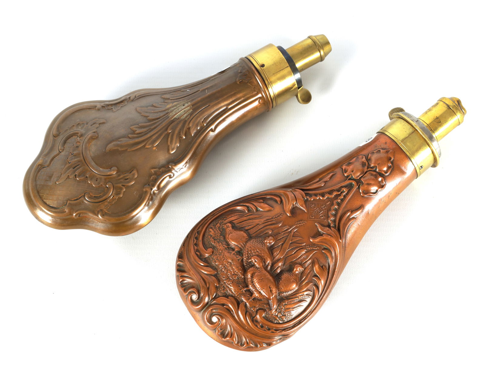 TWO 19TH CENTURY COPPER AND BRASS POWDER FLASKS, ONE SIGNED JAMES DIXON & SONS: TWO 19TH CENTURY COPPER AND BRASS POWDER FLASKS, ONE SIGNED JAMES DIXON & SONS the signed flask embossed with partridges the other with embossed leafwork (2)