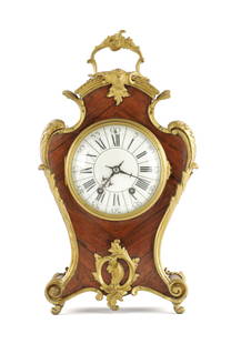 A LATE 19TH CENTURY WALNUT AND ORMOLU MOUNTED MATEL CLOCK: A LATE 19TH CENTURY WALNUT AND ORMOLU MOUNTED MATEL CLOCK, the book matched veneered case with acanthus leaf ormolu mounts enclosing an enamel dial with Roman numerals fronting an eight day spring dri